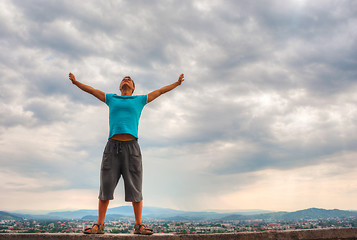 Image showing Young man staying with raised hands