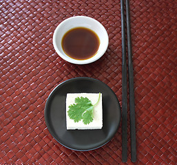 Image showing tofu square on a round black dish