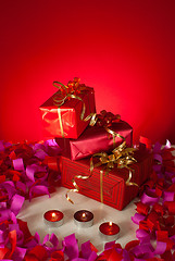 Image showing Christmas gifts and candles over red background