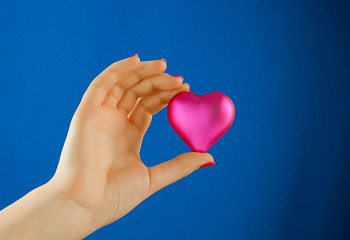 Image showing Hand holds a heart shaped gift against blue background