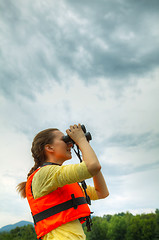 Image showing Young woman looking through binoculars