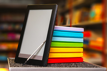 Image showing Stack of colorful books with electronic book reader