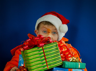 Image showing Surprised boy looking from behind the Christmas presents