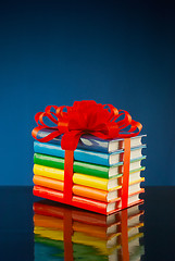 Image showing Stack of colorful books tied up with red ribbon