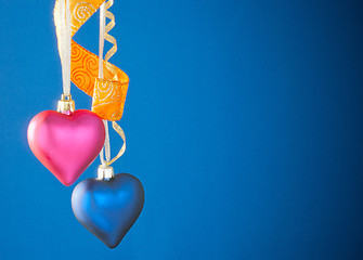 Image showing Two heart shaped toys hanging against blue background