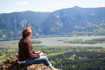 Image showing Woman sits at the top of a cliff