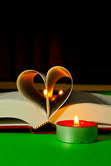 Image showing Open book with burning candle