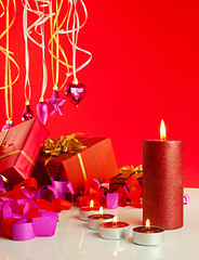 Image showing Christmas gifts and candles over red background