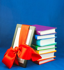 Image showing Electronic book reader tied up with red ribbon with stack of books