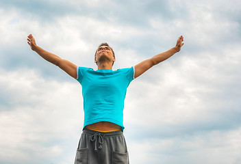 Image showing Young man staying with raised hands 