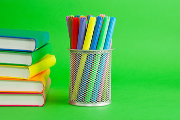 Image showing Stacks of colorful books and socket with felt pens