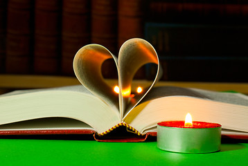 Image showing Open book with burning candle