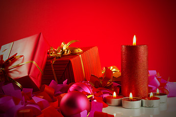 Image showing Christmas gifts and candles over red background