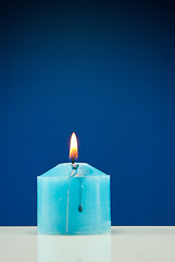 Image showing Close up of burning candle against dark blue background