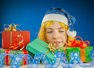 Image showing Surprised teen girl looking from behind the Christmas presents