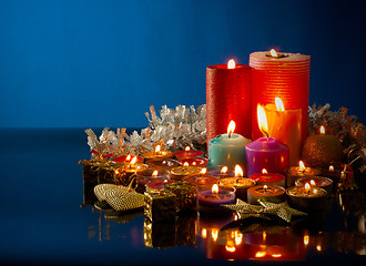 Image showing A lot of burning colorful candles against dark blue background