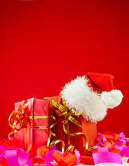 Image showing Christmas presents with Santa's hat against red background