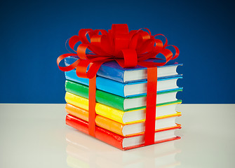 Image showing Stack of colorful books tied up with red ribbon