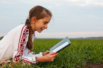 Image showing Teen girl with electronic book laying on grass