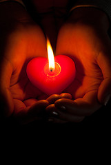 Image showing Human hands hold heart shaped burning candle