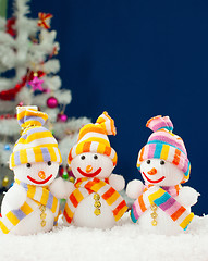 Image showing Three snowmen in front of the decorated white evergreen tree ove