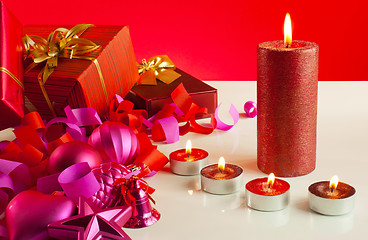 Image showing Christmas gifts and four candles over red background