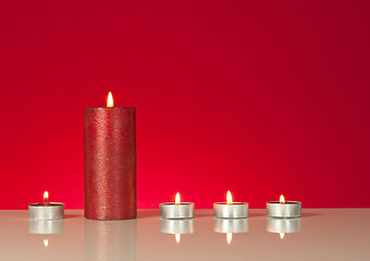 Image showing Five burning candles over red background