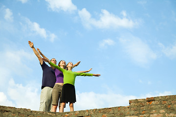 Image showing Three young people staying with raised hands
