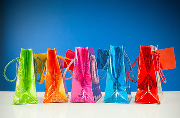 Image showing Row of colorful bags against blue background