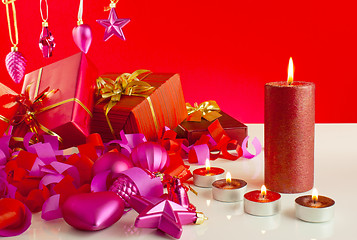 Image showing Christmas gifts with candles over red background