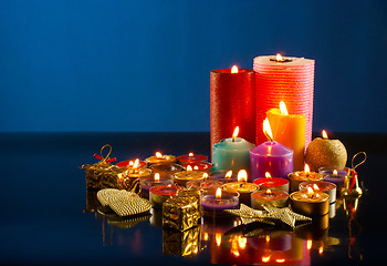 Image showing A lot of burning colorful candles against dark blue background