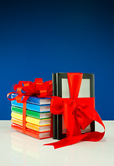 Image showing Books tied up with ribbon and electronic book reader against blue background