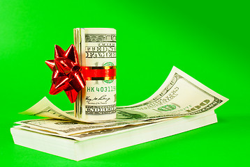 Image showing Roll of US dollars tied up with ribbon on the stack of bills