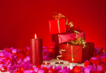 Image showing Christmas gifts and candles over red background