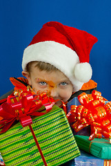 Image showing Surprised boy looking from behind the Christmas presents