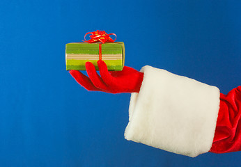 Image showing Santa's hand holding a present over blue background
