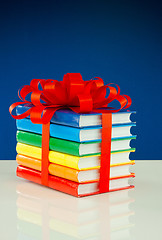 Image showing Stack of colorful books tied up with red ribbon