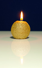 Image showing Golden burning candle against blue background