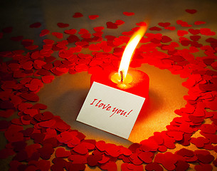 Image showing Burning heart shaped candle and a card