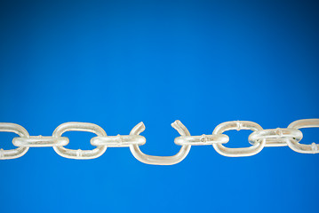 Image showing Steel chain with a broken link over blue background