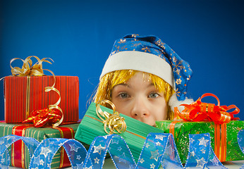 Image showing Surprised teen girl looking from behind the Christmas presents