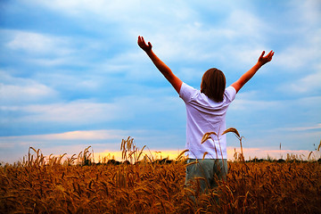 Image showing Young man staying with raised hands at sunset time