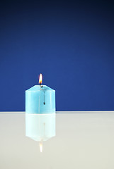 Image showing Close up of burning candle against dark blue background