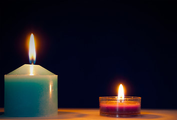 Image showing Two burning candles against dark blue background