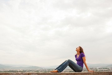 Image showing Young woman sitting outdoors against blue sky