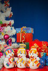 Image showing Three snowmen in front of the Christmas presents over the blue b