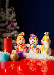 Image showing Three snowmen and burning candles over the blue background