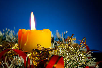 Image showing Burning candle with Christmas decorations against blue background