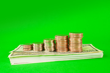 Image showing Coins stacked in bars laying on stack of 100 dollar bills