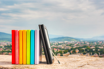 Image showing Stack of colorful books with e-book reader